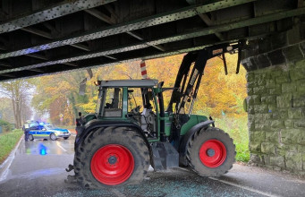 Traktor mit Frontlader verkeilt sich unter Brücke